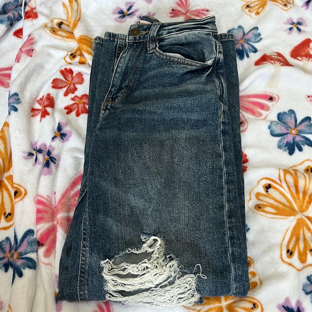 Blue rippped jeans worn one or twice wide leg